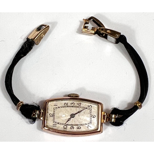 712 - A 1930's 9 carat hallmarked gold wristwatch of rounded rectangular form, on black fibre strap, gross... 