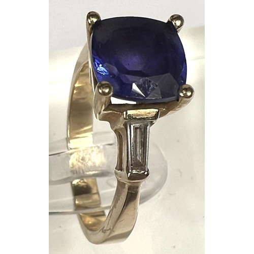 750 - A modern ladies dress ring set square cut tanzanite with diamond baton to each shoulder, the yellow ... 