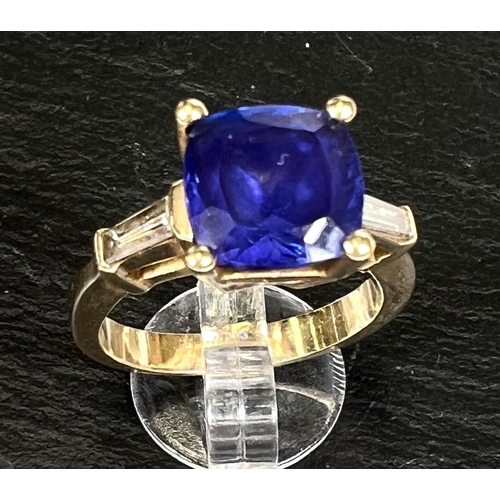 750 - A modern ladies dress ring set square cut tanzanite with diamond baton to each shoulder, the yellow ... 