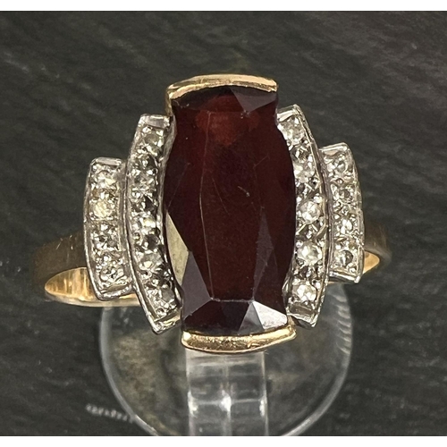 753 - An Art Deco style dress ring set garnet surrounded by 18 small diamonds, 18 carat yellow gold shank,... 