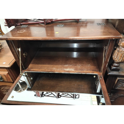 891 - A Jacobean style carved oak drinks cabinet with fall front over drawer and double cupboard