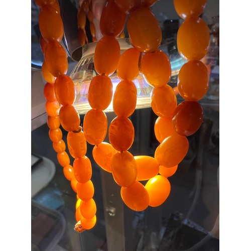 684 - A string of slightly graduating amber beads, length 98cm, largest bead 1.2cm, 32.7gm