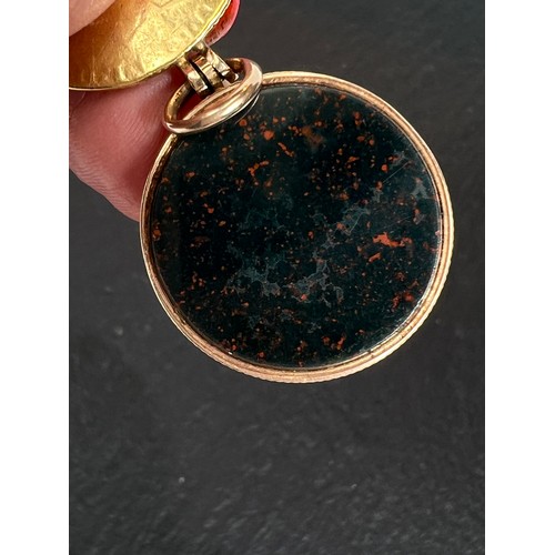 680A - A George III spade guinea (date worn) in gold and bloodstone locket (tests as 14ct), 14.0gm