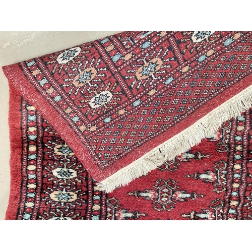 193C - A modern red ground hand knotted Pakistan Bokhara runner and similar smaller rug