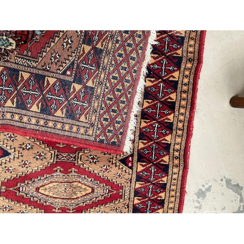 193C - A modern red ground hand knotted Pakistan Bokhara runner and similar smaller rug