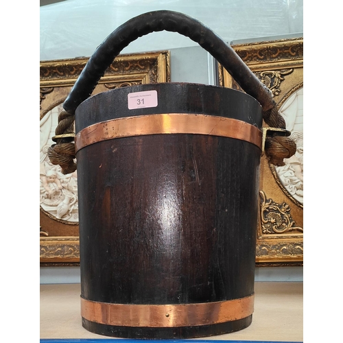31 - An oak bucket with copper bands, leather covered rope handle with brass mounts