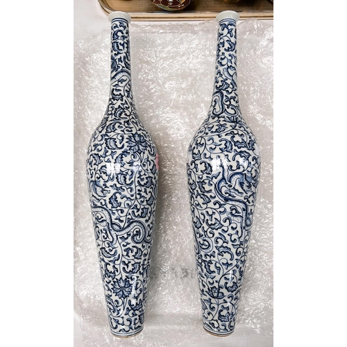 495 - A Chinese pair of vases, tall and thin with thin neck and foot with scrawling blue and white decorat... 