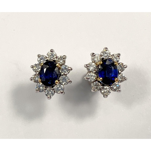 660 - A pair of 18ct white gold earrings set with large central sapphire. Oval cut, length 7mm surrounded ...