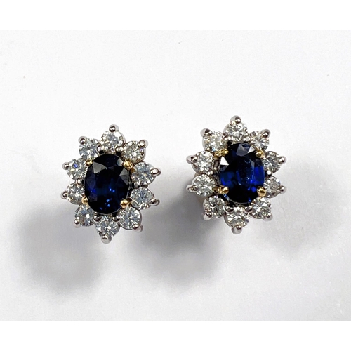 660 - A pair of 18ct white gold earrings set with large central sapphire. Oval cut, length 7mm surrounded ... 