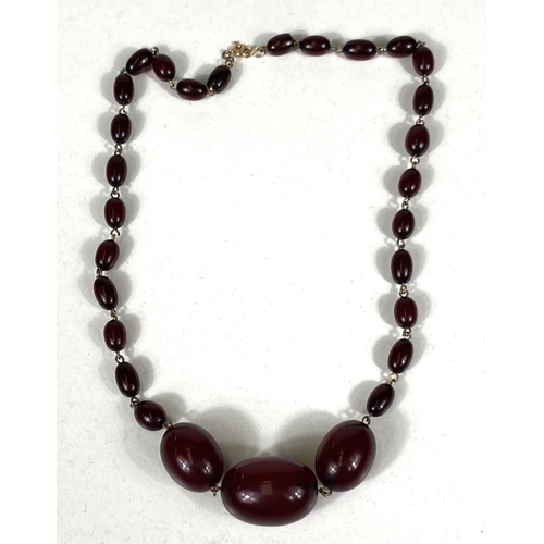 670 - A cherry bakelite amber necklace, graduating with internal swirls, largest 2.7cm approx. clasp stamp... 