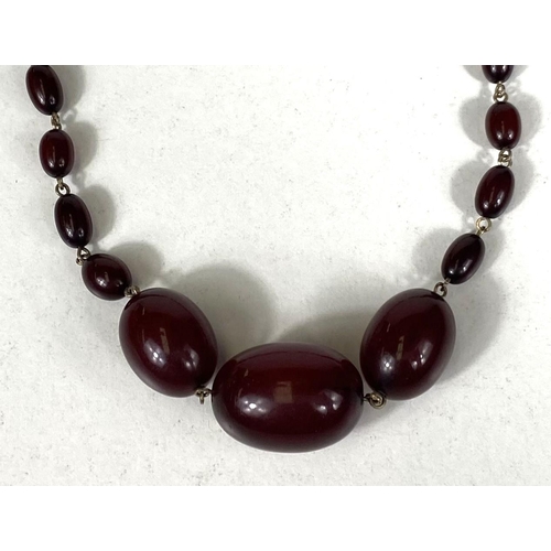 670 - A cherry bakelite amber necklace, graduating with internal swirls, largest 2.7cm approx. clasp stamp... 