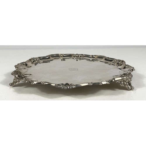 713 - A hallmarked silver circular salver in the Georgian style with scroll and shell border, London 1926,... 