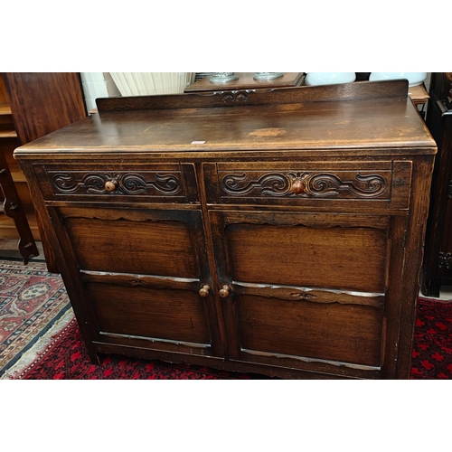 911 - A 1930's oak Jacobean style sideboard of 2 cupboards and 2 drawers