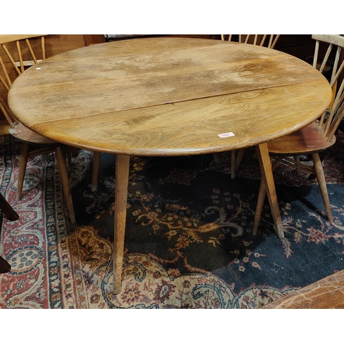 1032 - A 1960's Ercol, light elm, circular drop leaf dining table.