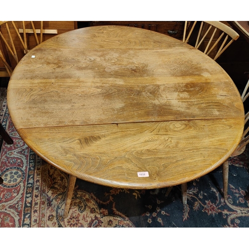 1032 - A 1960's Ercol, light elm, circular drop leaf dining table.