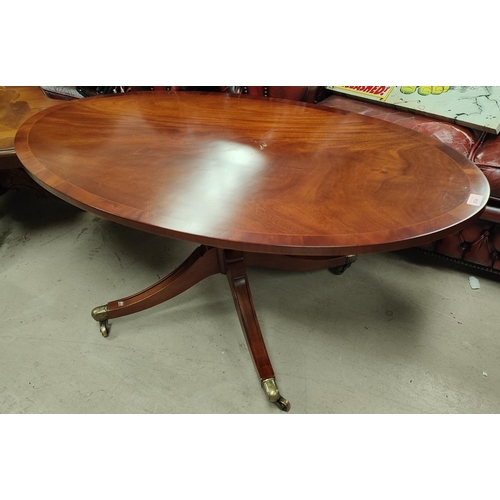 854 - An inlaid oval reproduction coffee table on four splay feet with brass casters in the 'Reprodoux' ma... 