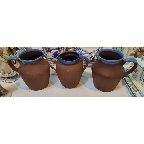 439A - Three vintage terracotta milk jugs with blue rims