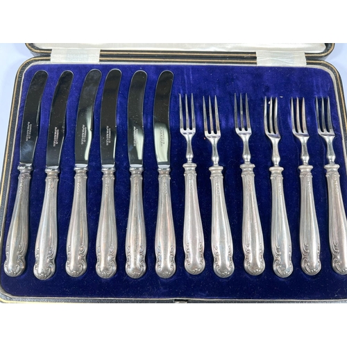 604 - A cased set of 6 silver handled knives and forks, filled centres, Harrods case