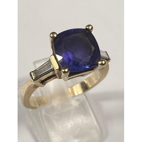 664 - A modern ladies dress ring set square cut tanzanite with diamond baton to each shoulder, the yellow ... 