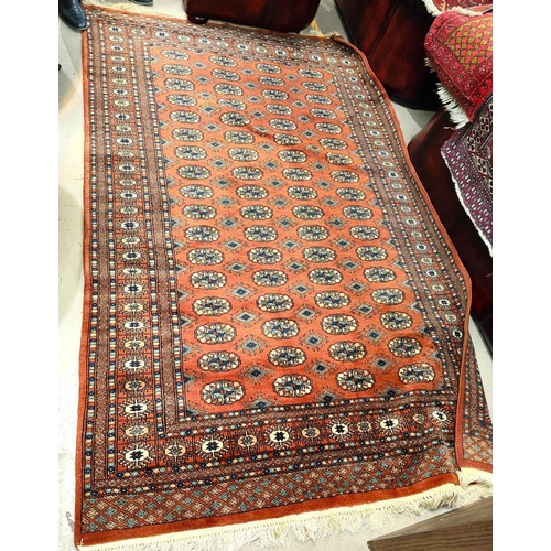 837 - A 20th century hand knotted rust ground Bokhara carpet with four lines of guls to centre,  152 x 232... 