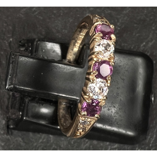 579 - A 9 carat hallmarked gold ring set 3 red stones alternately with 2 clear stones, 2 small graduating ... 