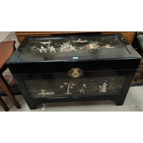 893 - A mid 20th century Chinese black lacquer blanket chest with simulated hardstone relief figures in pr... 