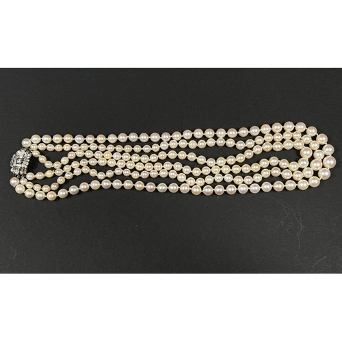 613 - A triple strand pearl necklace, the white metal clasp set multiple diamonds