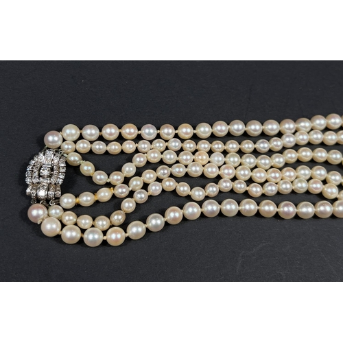 613 - A triple strand pearl necklace, the white metal clasp set multiple diamonds