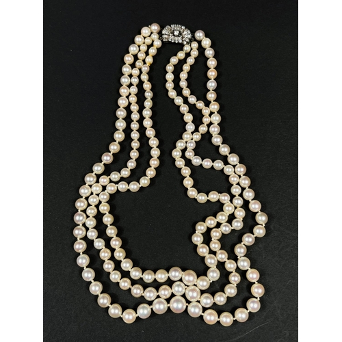 613 - A triple strand pearl necklace, the white metal clasp set multiple diamonds