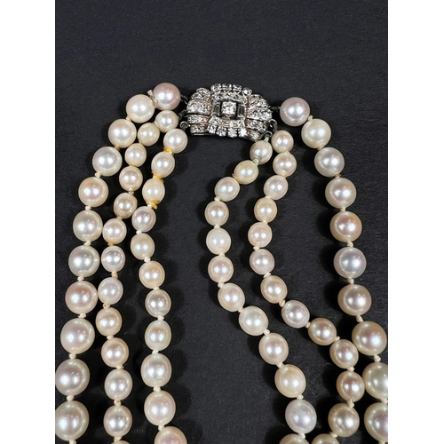 613 - A triple strand pearl necklace, the white metal clasp set multiple diamonds