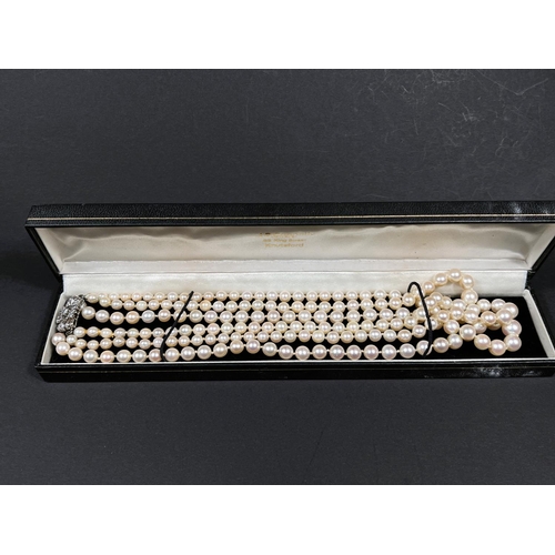 613 - A triple strand pearl necklace, the white metal clasp set multiple diamonds