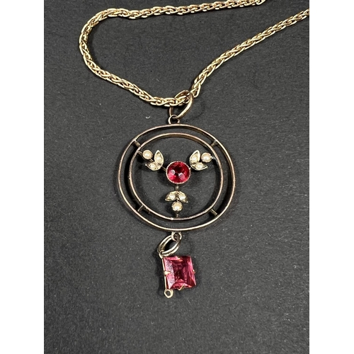 617 - A yellow metal circular pendant set seed pearls and  red stones, unmarked, on 9 carat hallmarke... 