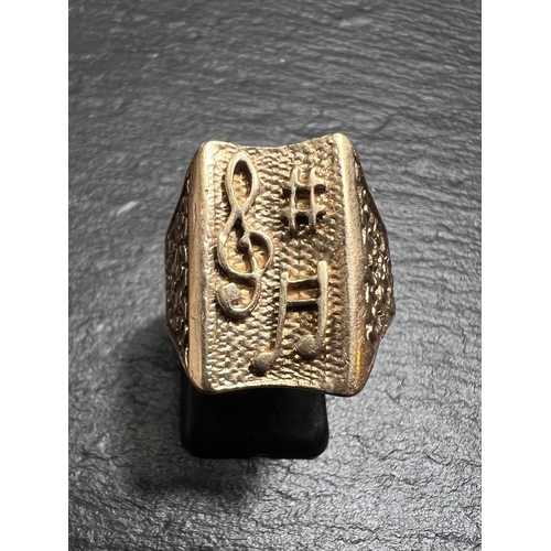 676 - A 9ct hallmarked gold embossed signet ring with musical decoration, size S, 6.3gm