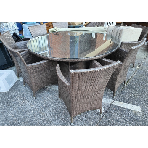 1010 - A large garden table in woven fibre circular pedestal shaped with 8 chairs and sun shade