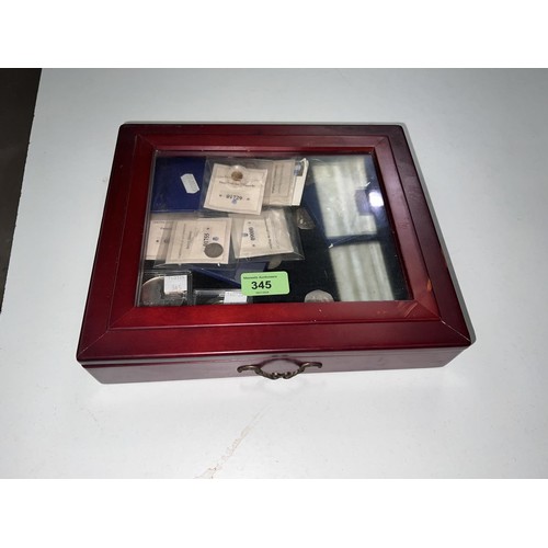 345 - A mahogany finish collectors cabinet containing various items including a 0.5gm gold coin and 2 silv... 