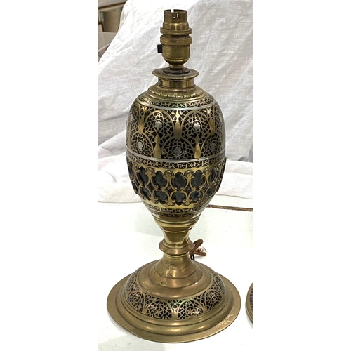 65 - A Middle Eastern pair of brass table lamps of baluster form with silvered line and extensive fretwor... 