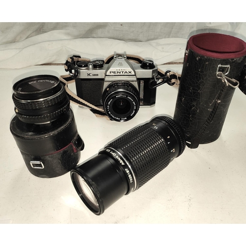 125 - A Pentax K1000 SLR camera with three lenses, 80mm - 200mm, 28mm and 50mm