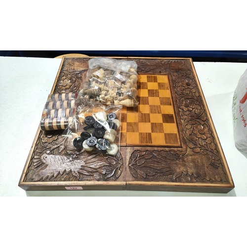 153 - A carved wooden folding chessboard with chess pieces and checkers, parrot carved decorative