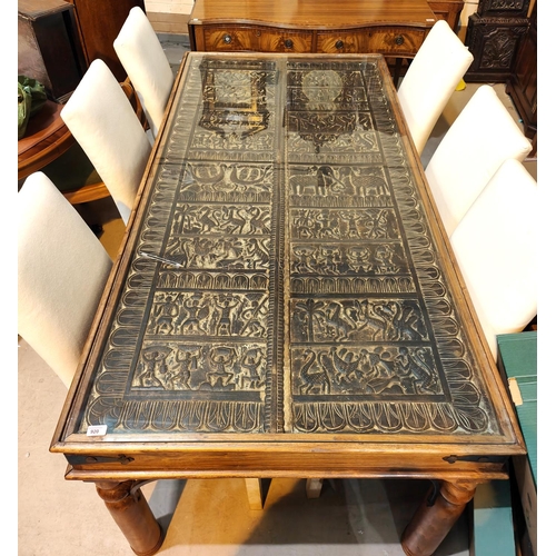 920 - An unusual dining table with carved African tribal panel under glass as table top, the panels having... 