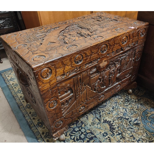 914 - A heavily carved Chinese chest with people and plants, hinged lid, length 78cm