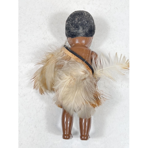 306A - A vintage plastic New Zealand Maori doll, 25cm, in a feathered cloak, 