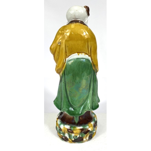 511B - A Chinese possibly Kangxi figure of a sage with bird and fruit, glazed in green, yellow and browns, ... 