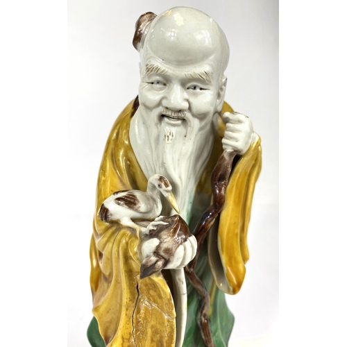 511B - A Chinese possibly Kangxi figure of a sage with bird and fruit, glazed in green, yellow and browns, ... 