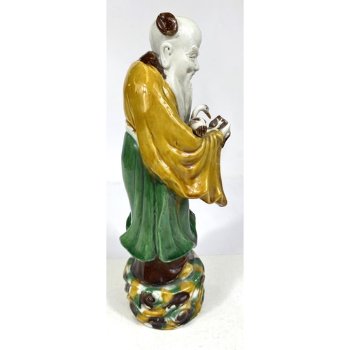 511B - A Chinese possibly Kangxi figure of a sage with bird and fruit, glazed in green, yellow and browns, ... 