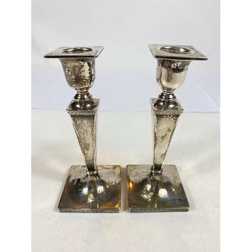 634 - A hallmarked silver pair of candlesticks with square tapering columns on square weighted bases, Shef... 