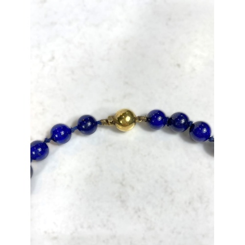 664 - A lapis lazuli bead necklace with 9 carat hallmarked gold ball clasp