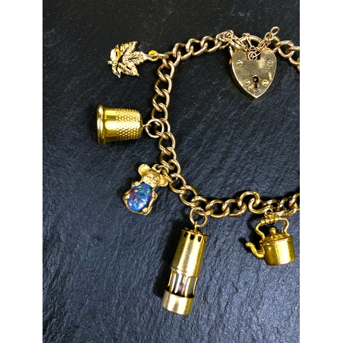 667 - A yellow metal charm bracelet, stamped 375, with heart lock and 7 charms (4 unmarked), gross weight ... 