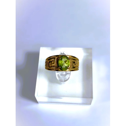 668 - A yellow metal wide ring, stamped 375, with Greek key style decoration, set oval peridot coloured st... 