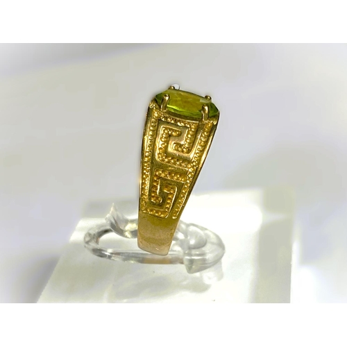 668 - A yellow metal wide ring, stamped 375, with Greek key style decoration, set oval peridot coloured st... 