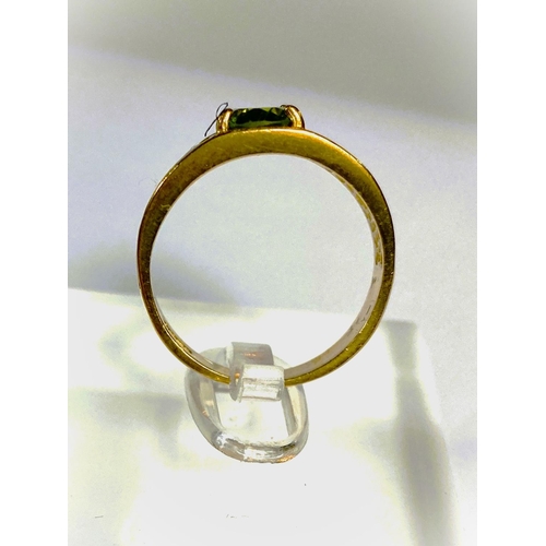 668 - A yellow metal wide ring, stamped 375, with Greek key style decoration, set oval peridot coloured st... 